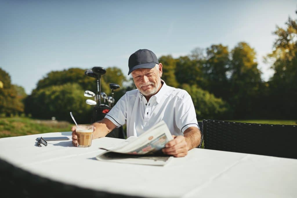 Smiling senior man drinking coffee after a round of golf