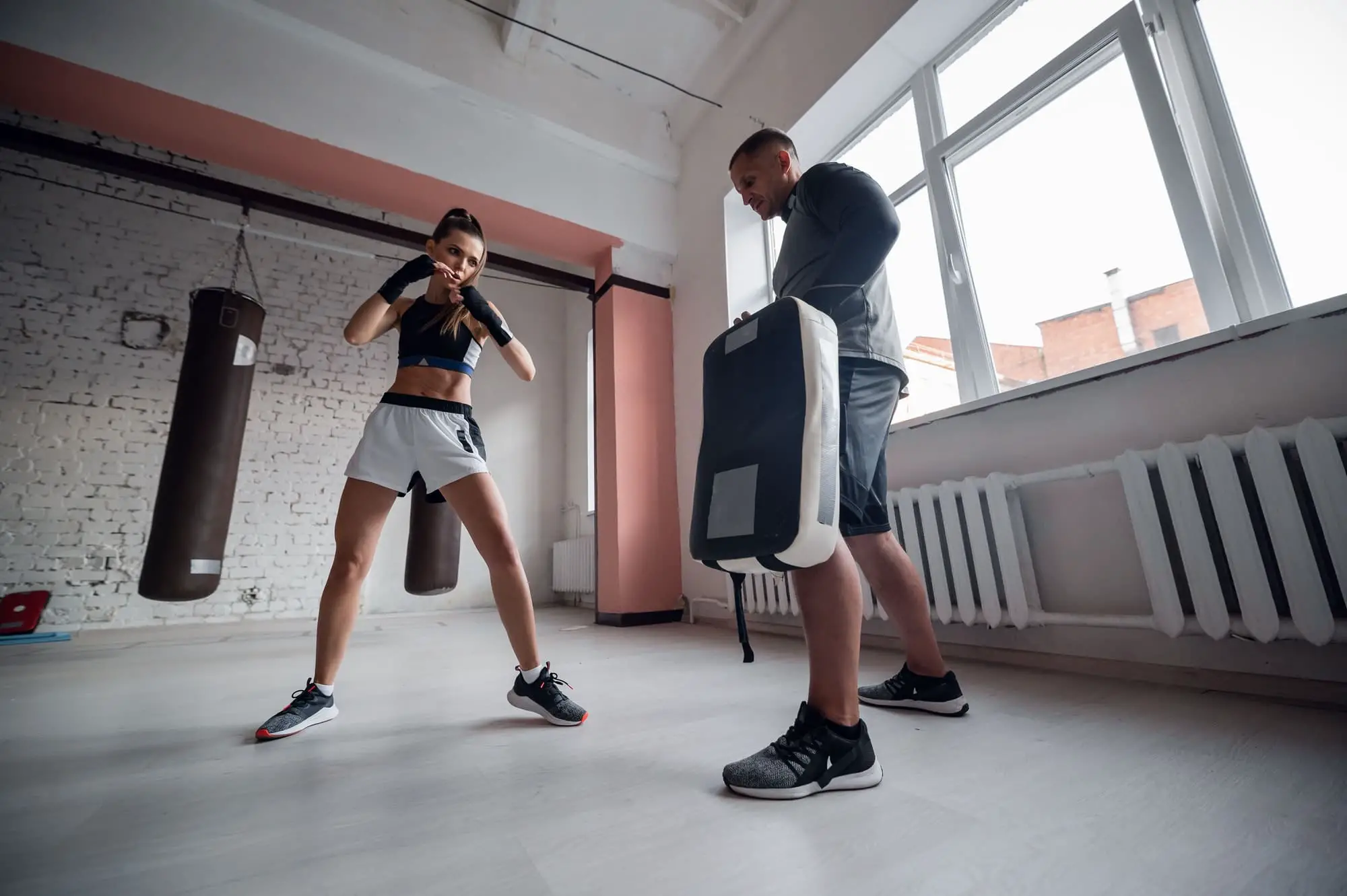 Training fight of male and female kickboxers. Practicing kicks and strikes on the boxing paw