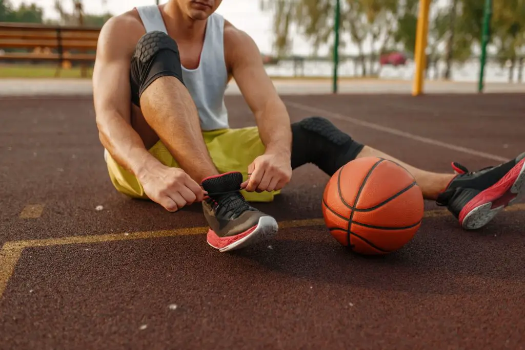 Basketball player tying laces on outdoor court