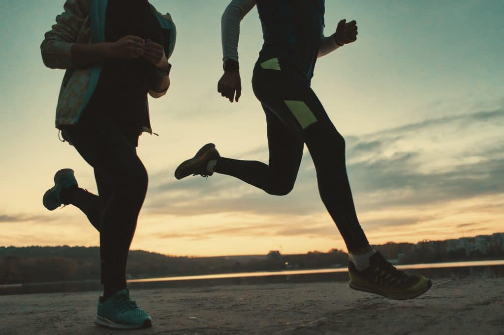 Sportive people legs running at sunrise