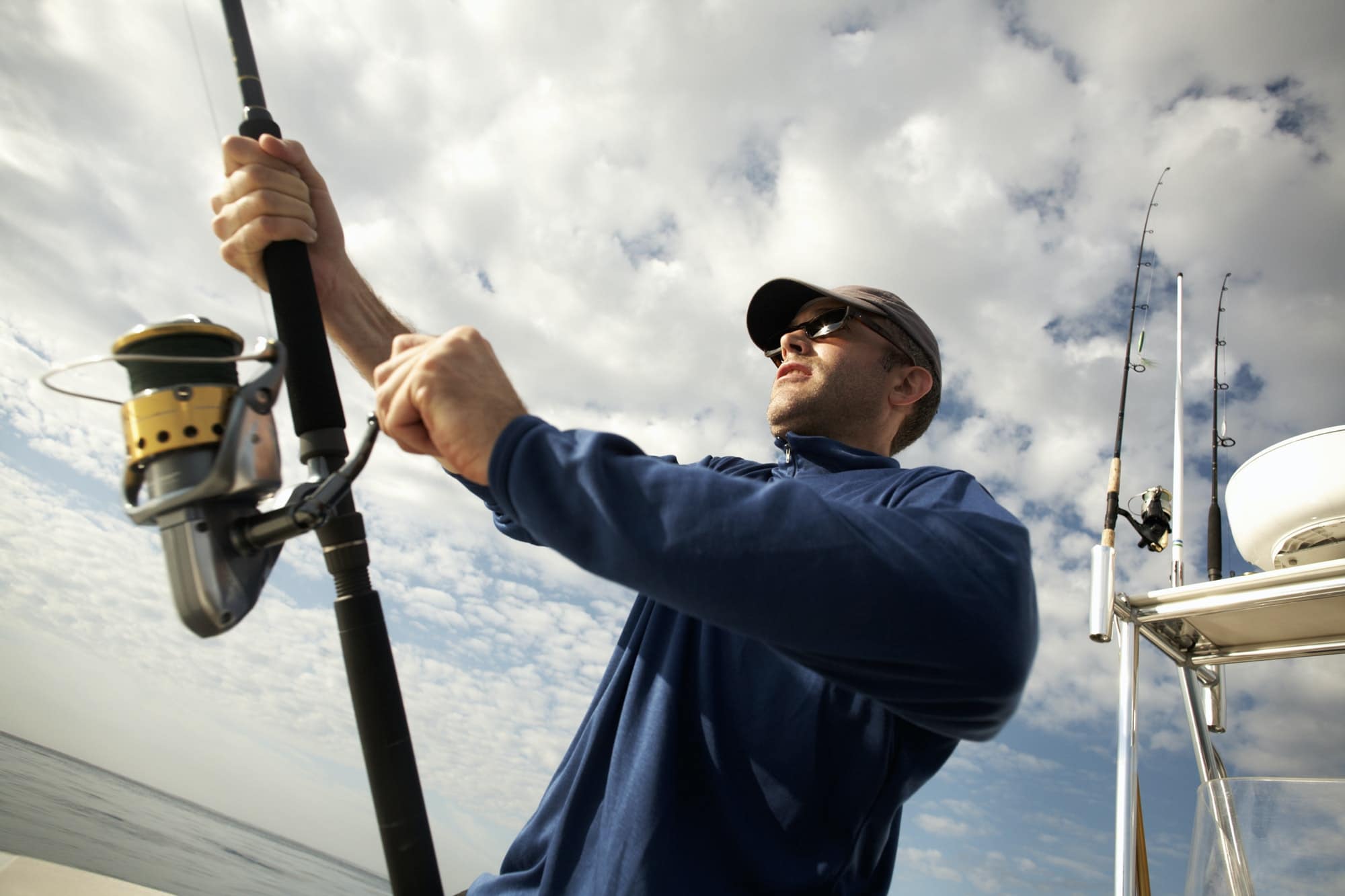 A man on a boat holding a fishing rod.