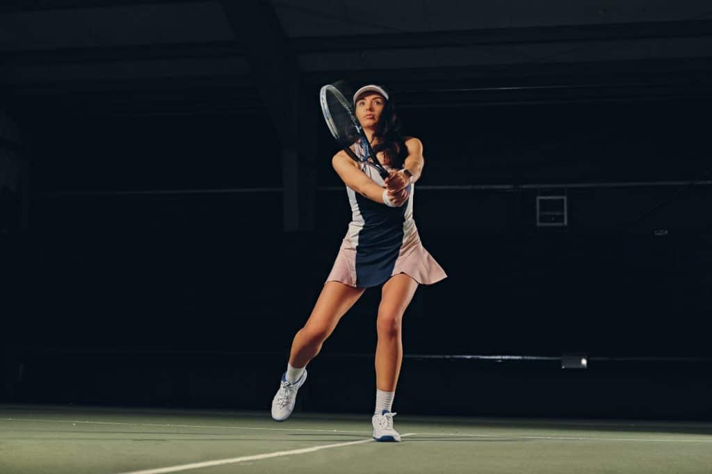 Female tennis player in a jump on a tennis court.