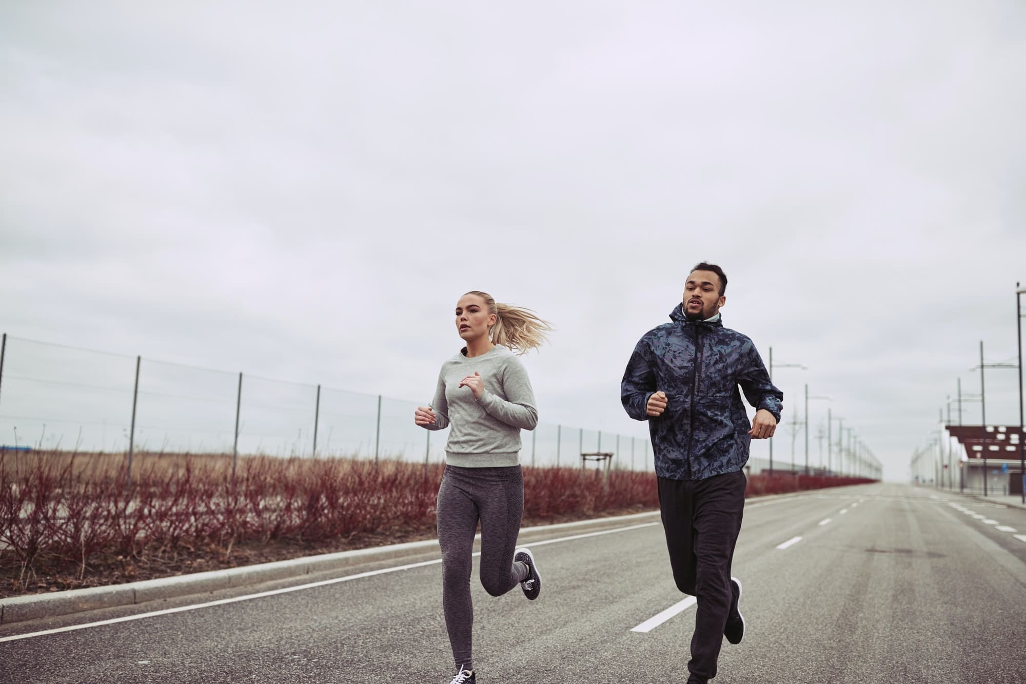 Diverse young couple running along a country road