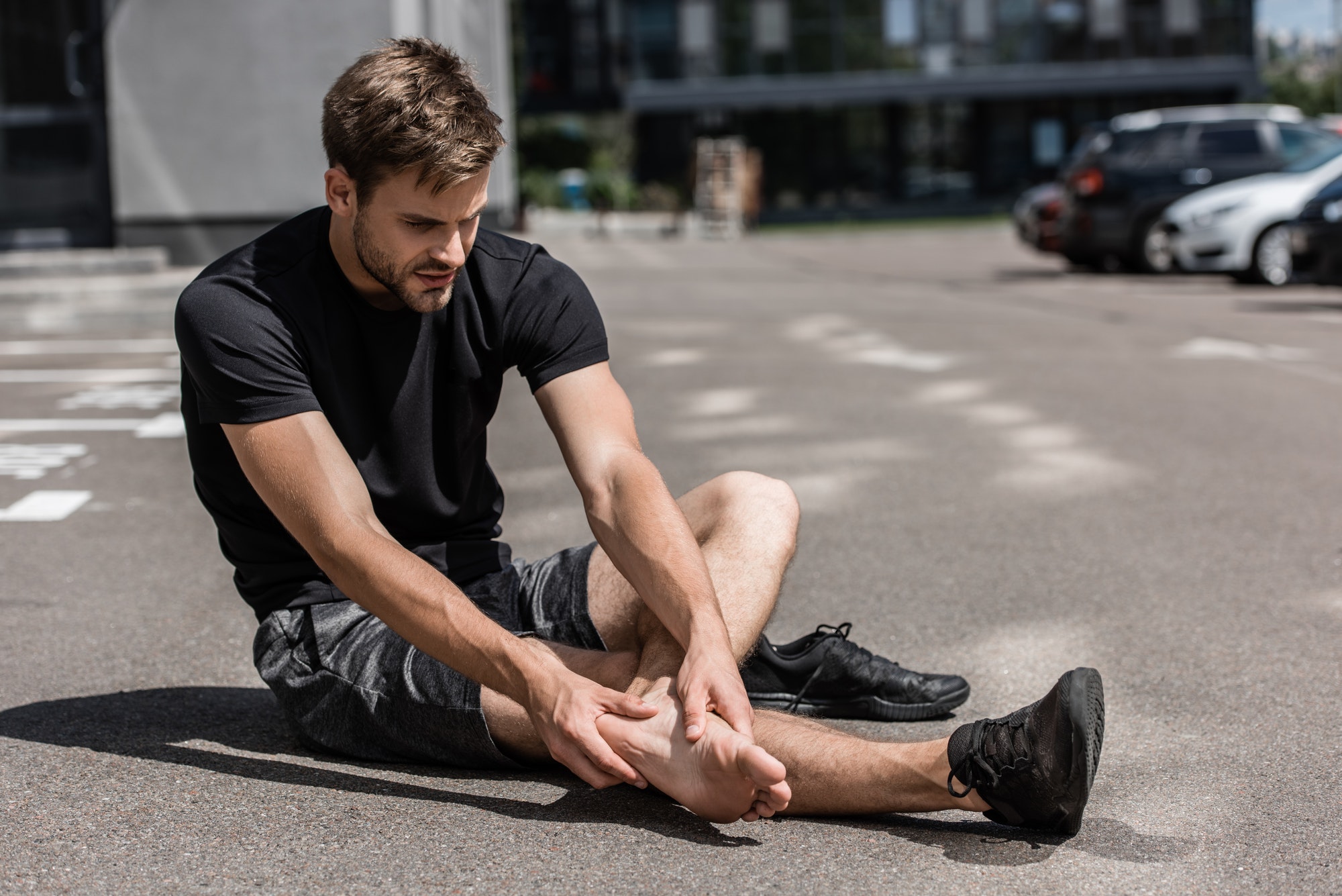 muscular bearded barefoot sportsman with foot pain on street