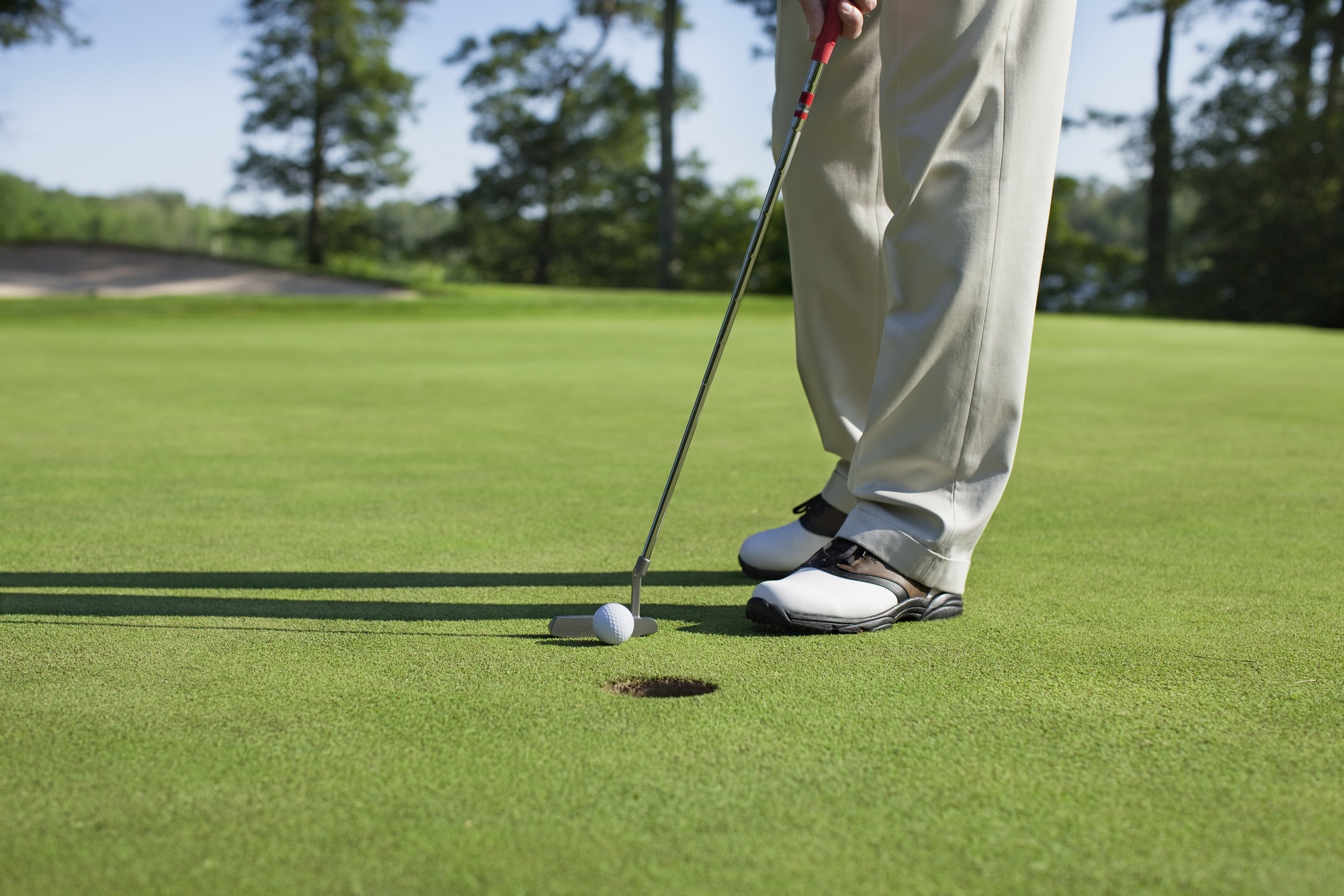 Golfer taps in a putt on a golf green