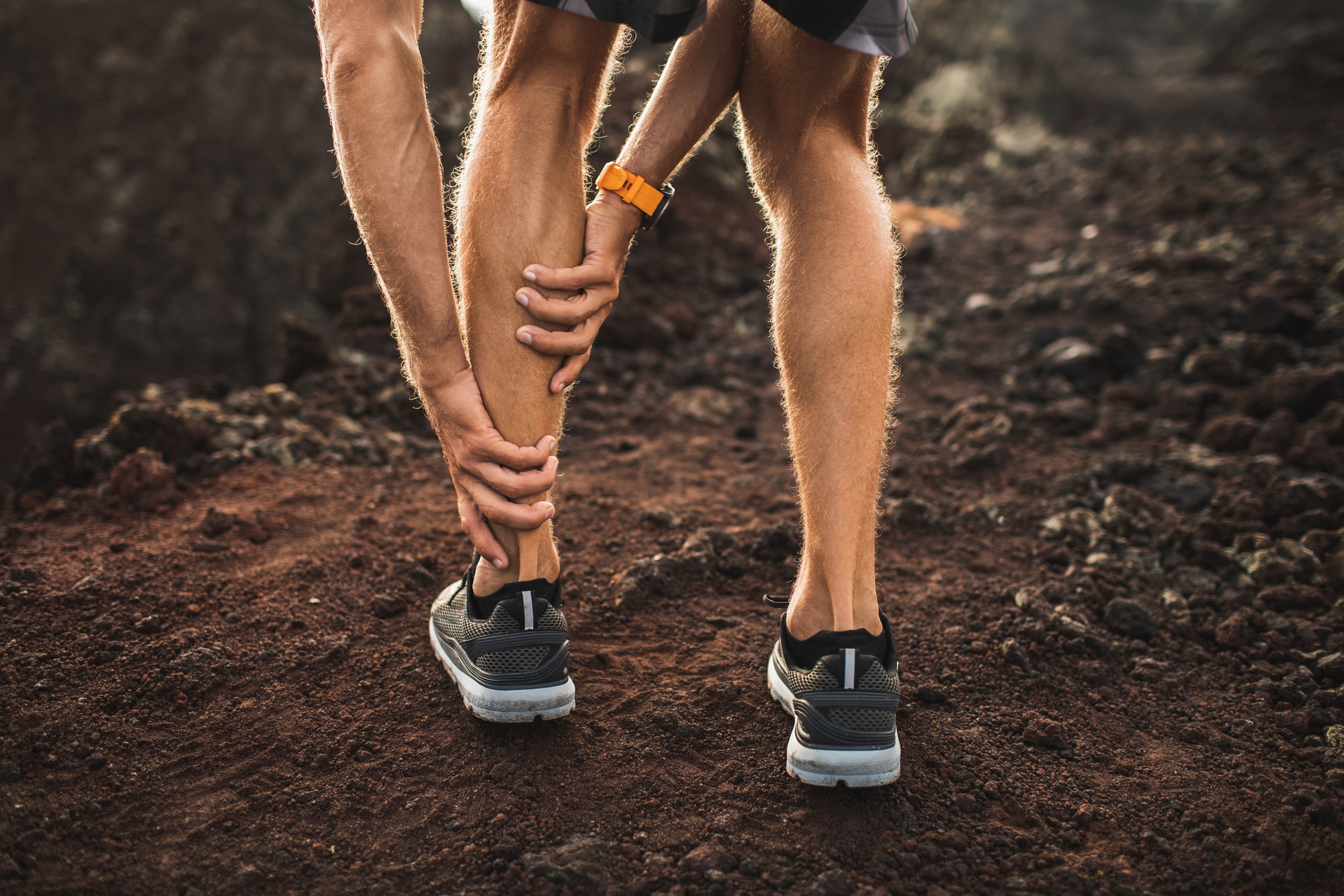 Male runner holding injured calf muscle and suffering with pain. Sprain ligament while running