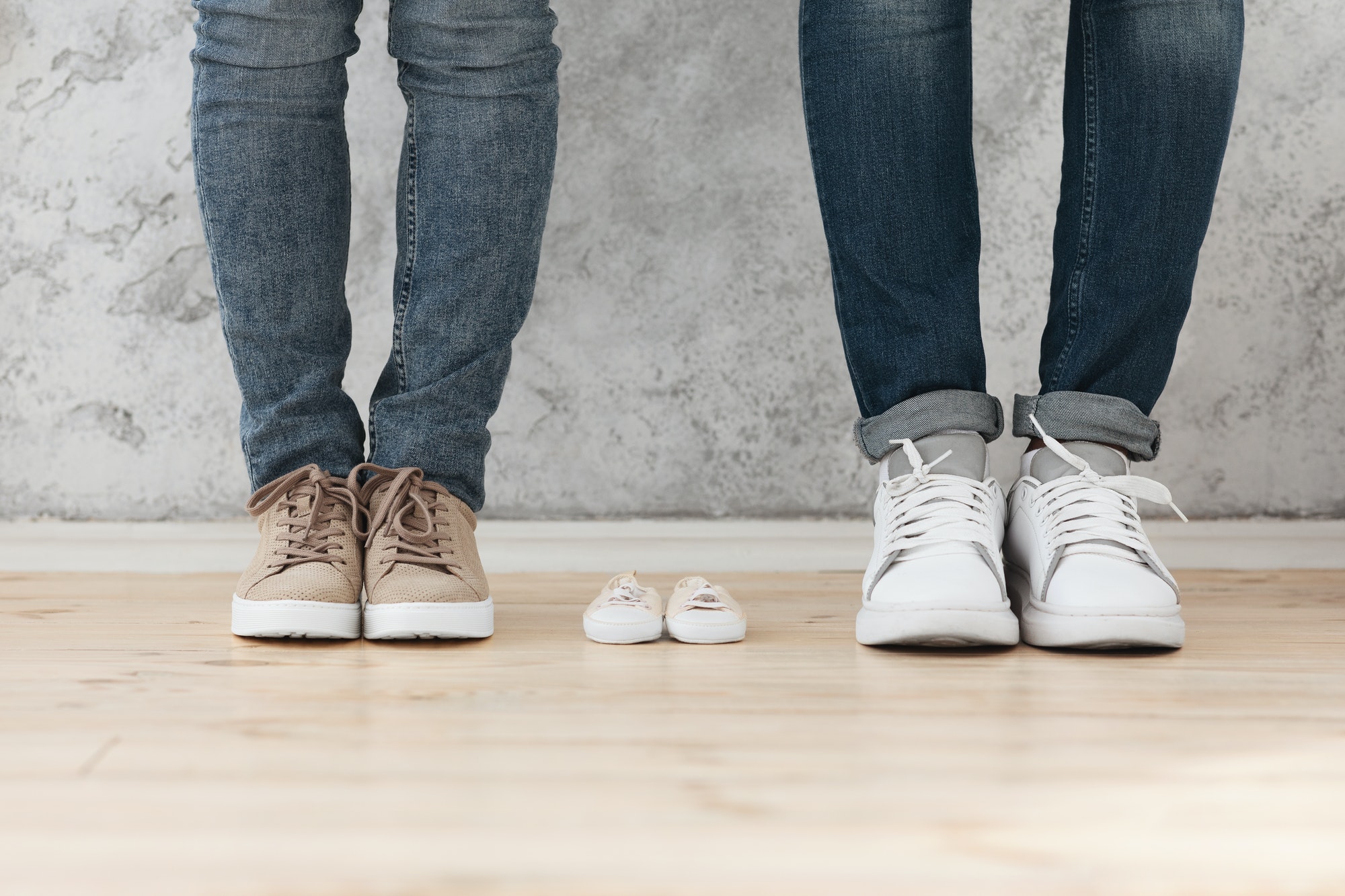 Man and woman standing next to small baby shoes