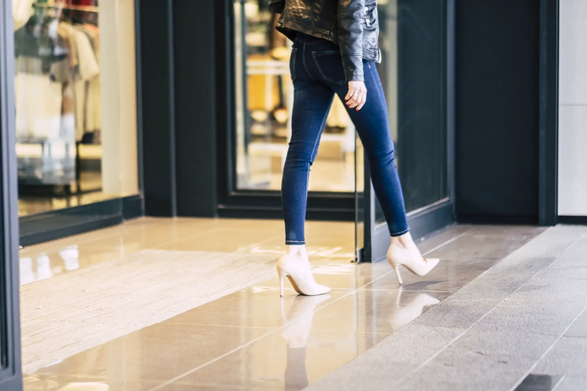 Fashion woman walking in stretch skinny jeans outside a store after shopping activity