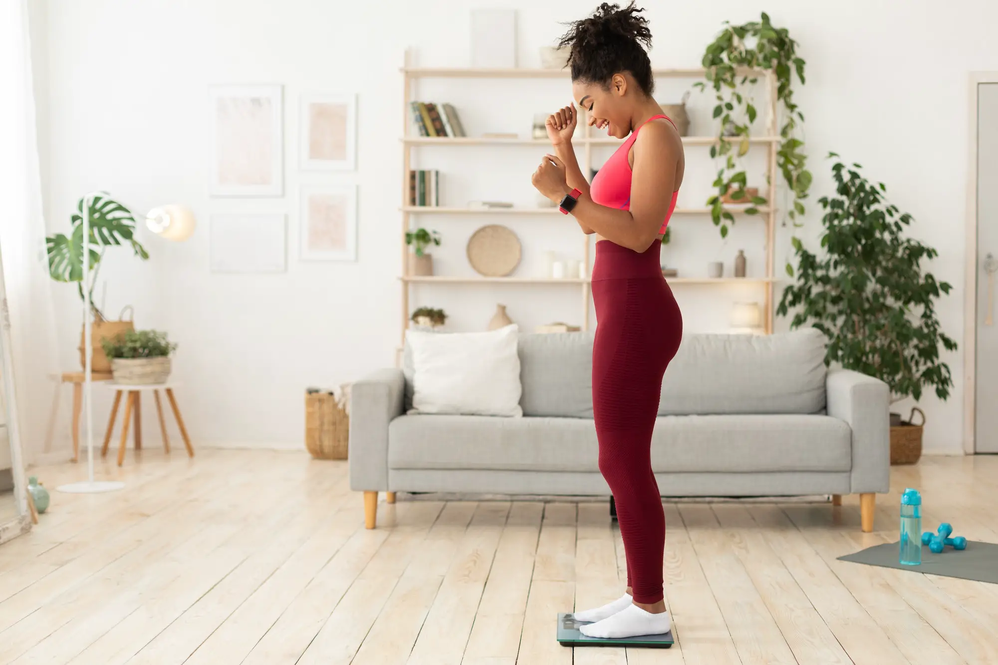 Joyful Black Woman Weighing Herself After Successful Weight Loss Indoors