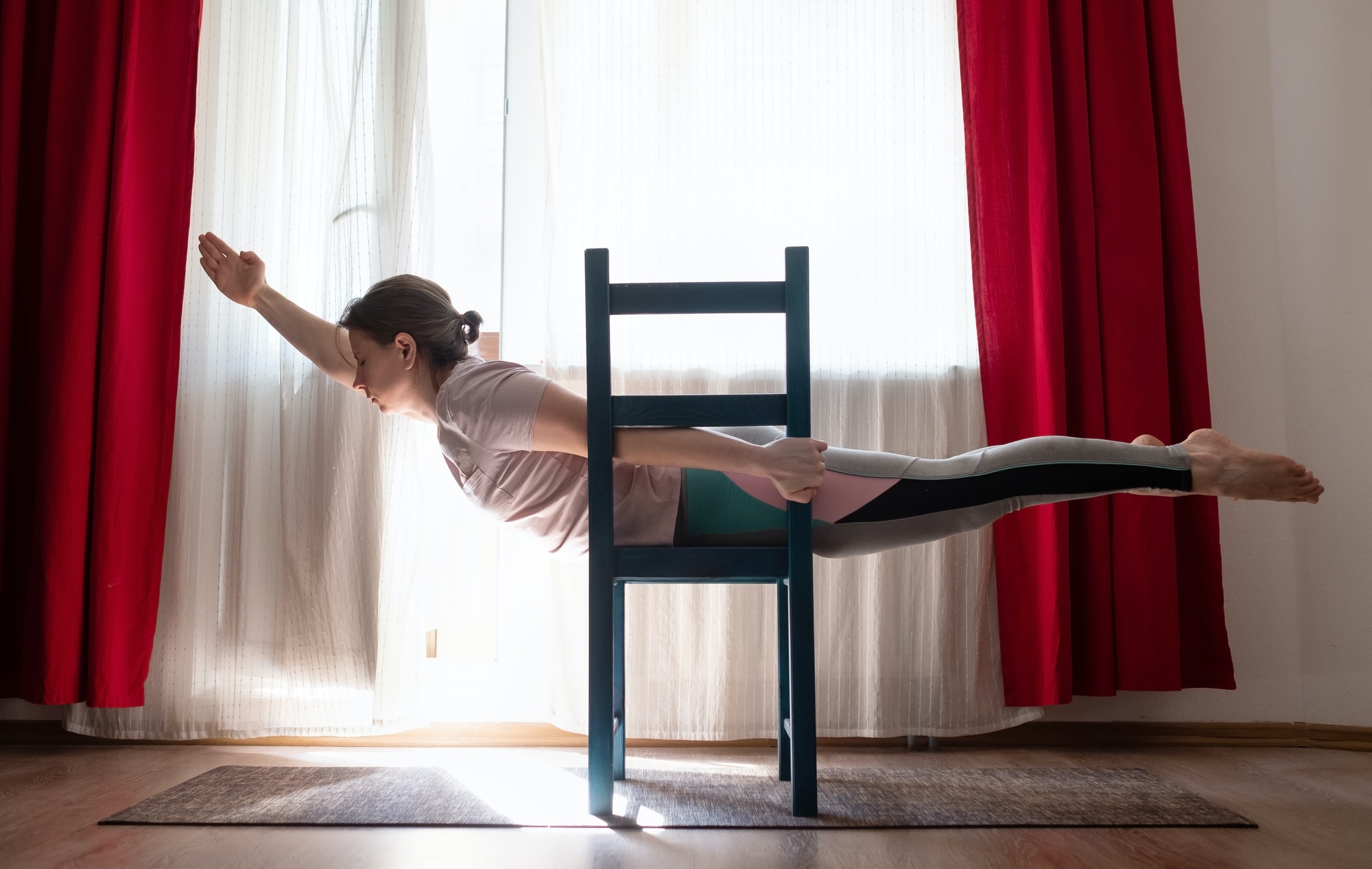 Young woman practicing yoga in Superman Pose or Viparita Shalabhasana using chair