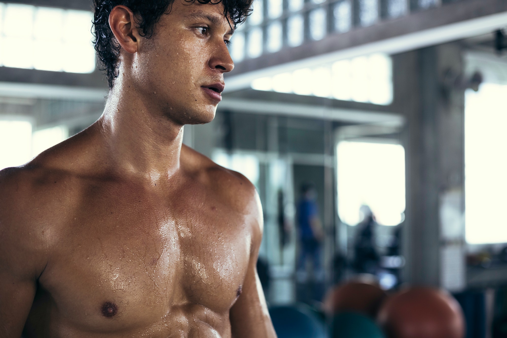 Muscular topless man sweating after workout exercise at fitness.