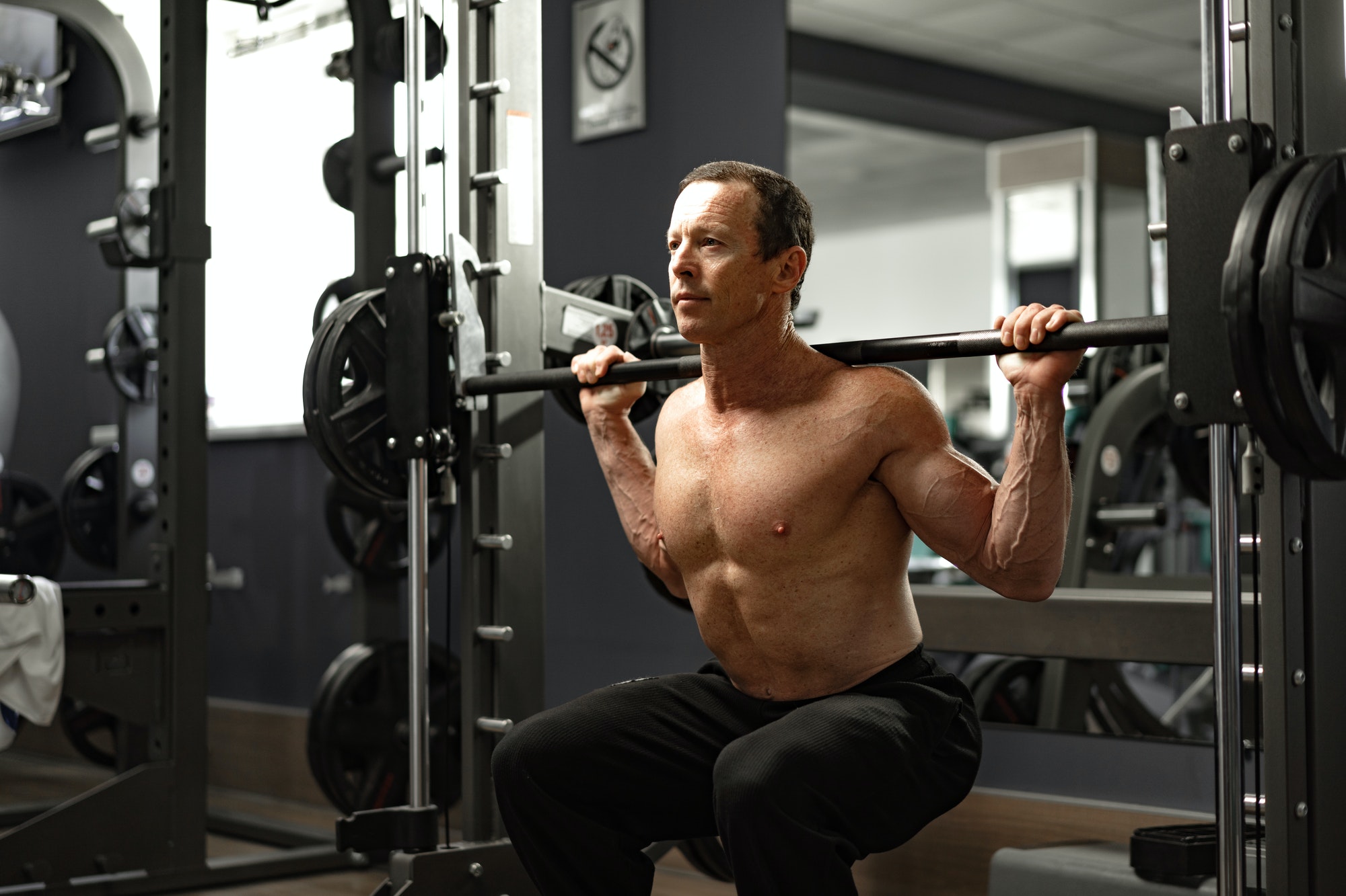 Senior man working out at the gym doing squats