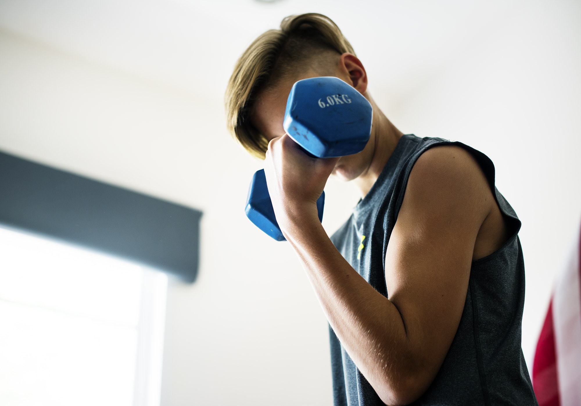 Young caucasian boy lifting dumbbell