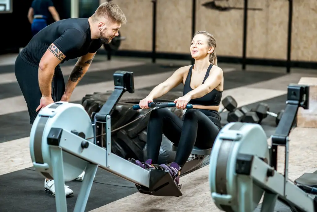 Coach training woman on the exercise machine