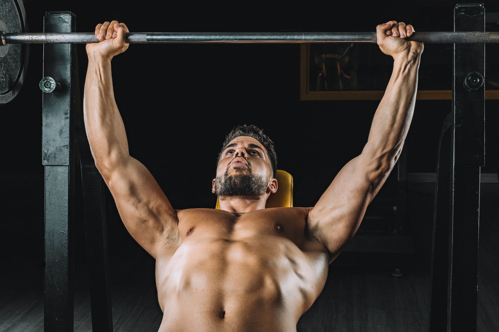 Man doing bench presses with weights in a gym