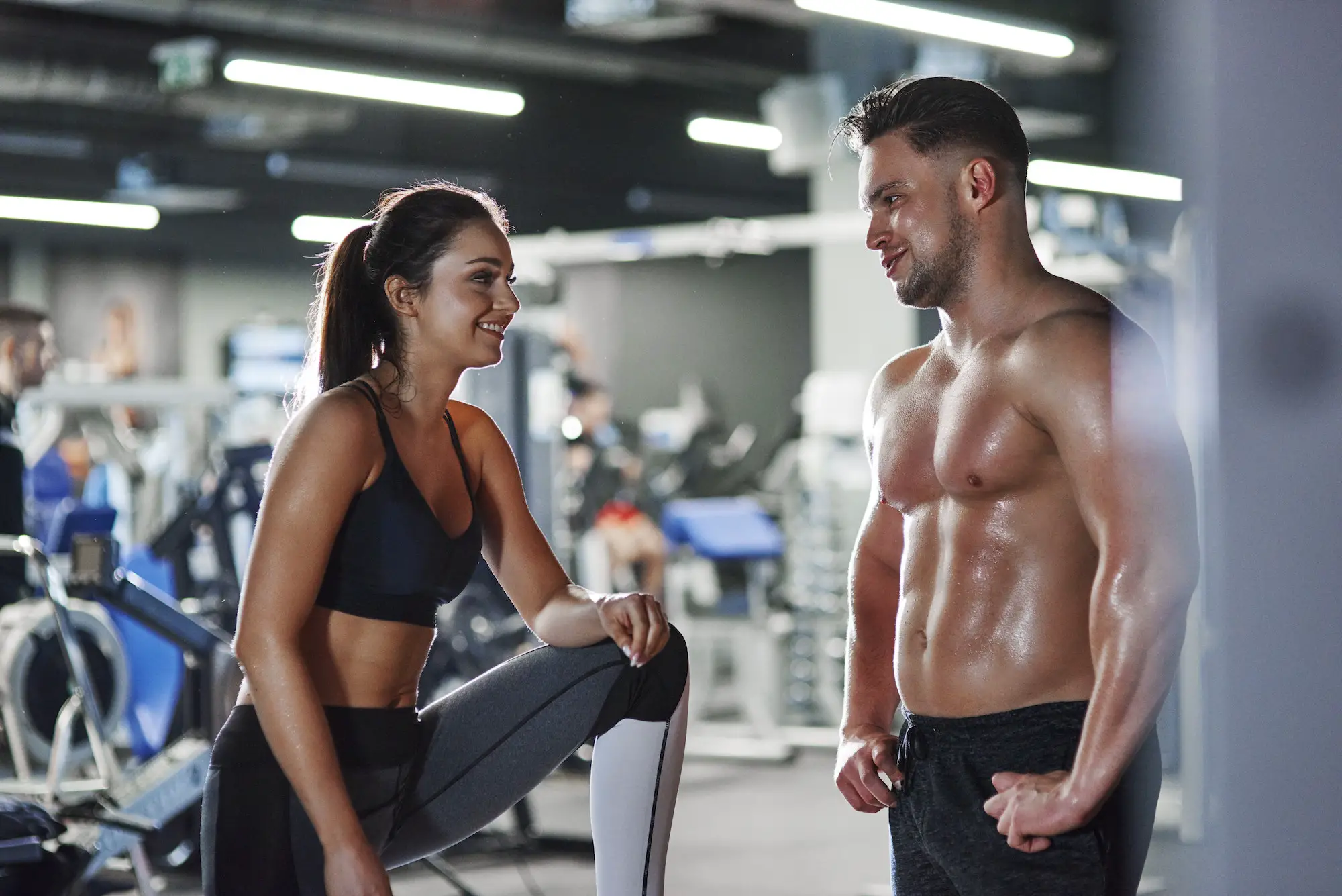 Smiling man and woman talking at the gym