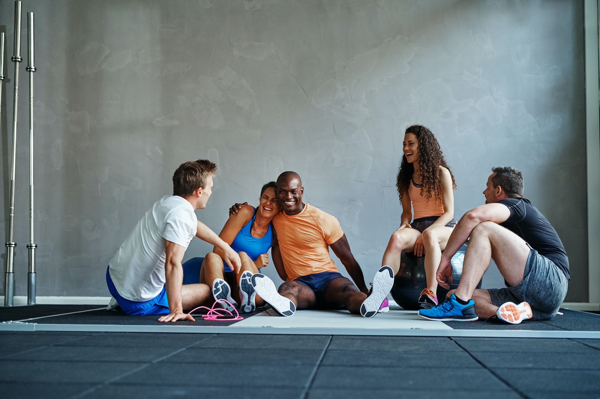 Friends talking and laughing together on a gym floor