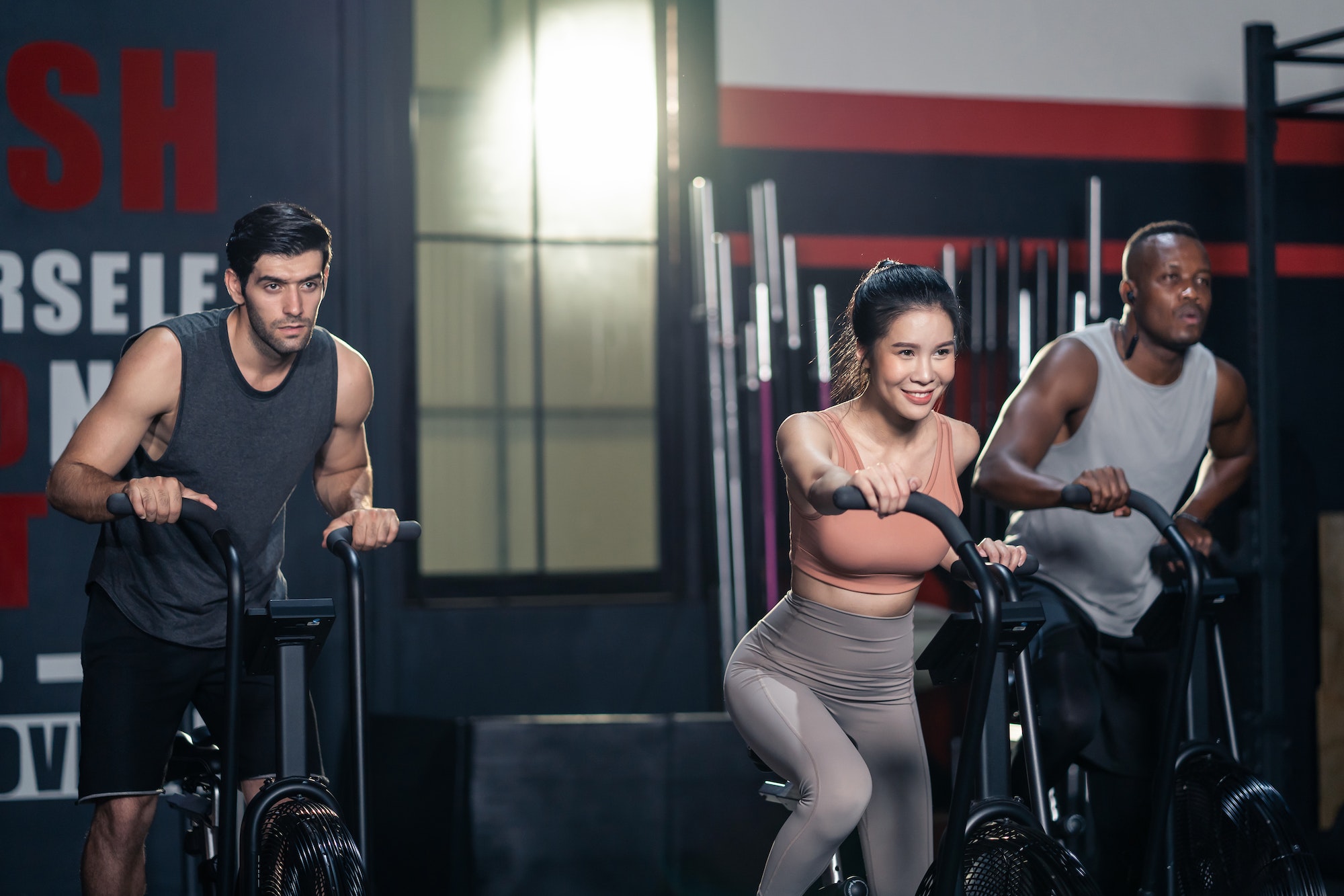 Group of multiethnic fitness trainer spinning bike exercise machine to build muscle at fitness