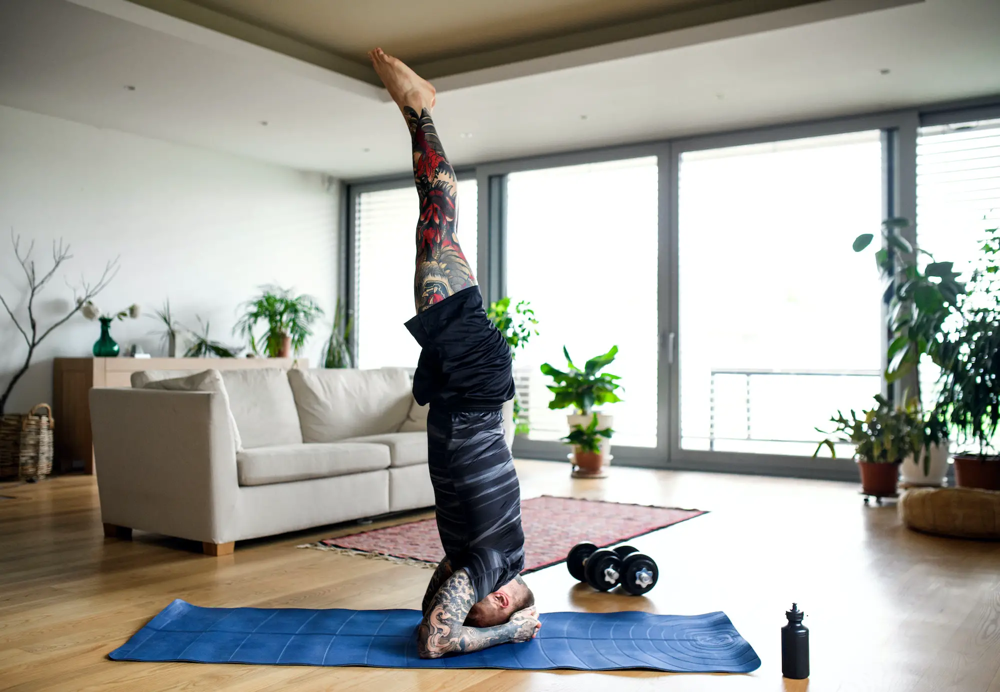 Young man doing workout exercise indoors at home, headstand