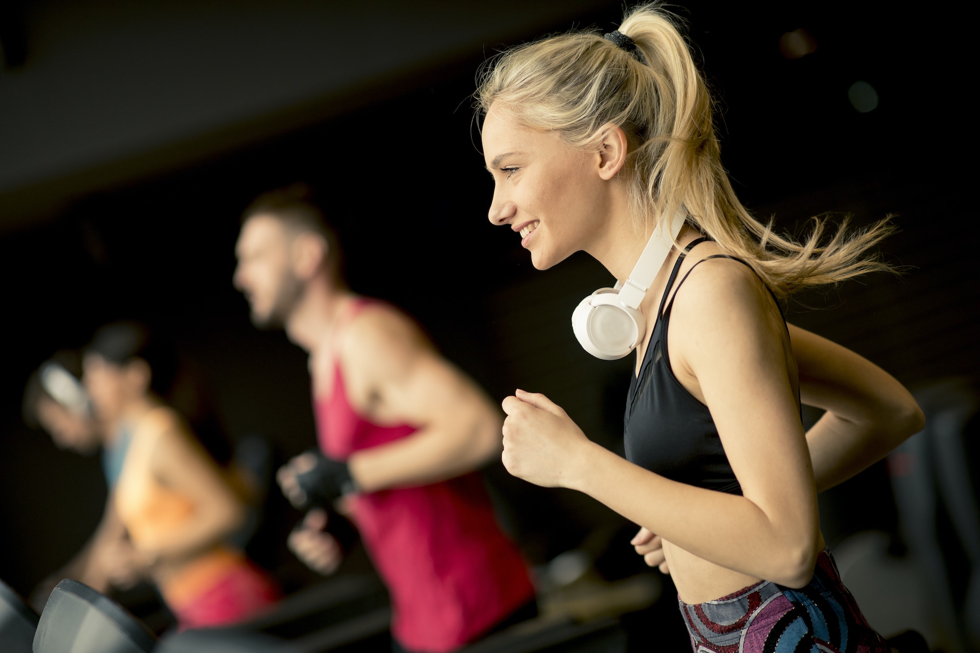 young people running on treadmills in modern gym